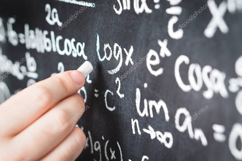 Professor writing mathematical formula and equation to blackboard in school classroom. College or university teacher or student with chalkboard. Science, education and math concept.