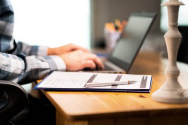 Gözlem formu, müşteri memnuniyeti geribildirim anket, kolej veya iş başvurusu için devam. Laptop ile yazma adam. Ev ya da araba sigorta sözleşmesi. Kağıt levha ve kalem masa üzerinde.