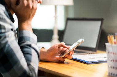 Tembel çalışan telefon kullanma office iş kaçınarak. El karşı yaslanmış ve smartphone ile sosyal medya internet tarama sıkılmış, üzgün ya da mutsuz bir adam. Kötü, verimsiz ve verimsiz çalışan.