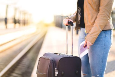 Tren ile bavul ve Bagaj için bekleyen kadın. Biletin ve pasaportun platformu elinde tutan ne? Parça içinde belgili tanımlık geçmiş.