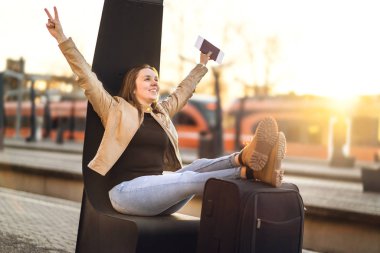 Sonunda tatil. Tren istasyonunda kutlayan kadın eğlenceye bırakın gezisi. Bacaklar ve bavul ve Bagaj üzerinde ayakkabı ile mutlu gülümseyen biri. Seyahat ve lifetyle kavramı.