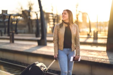 Kadın seyahat tren platformu günbatımında ayakta. Bavul, Bagaj ve Bagaj istasyonunda bekleyen gülümseyen kadın. Seyahat yaşam tarzı ve toplu taşıma kavramı.