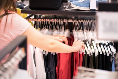 Kadın giyim moda deposundaki bir rafa bakarak. Kadın müşteri alışveriş. Satış ve giyim butik izni. Doğru boyutta malzeme çekme ellerini yakın çekim.