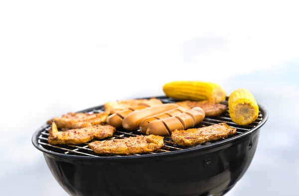 Grill with sausages, meat and corn. Outdoor grilling and barbeque. BBQ party, cookout or camping concept with negative copy space.