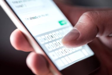 Kýsa mesaj ve sms ile smartphone gönderen adam. Adam manifatura ve istimal hareket eden telefon içinde karanlık gece geç saatlerde. İletişim veya sexting kavramı. Tipik ile cep telefonu klavye parmak. Ekran ışığı.