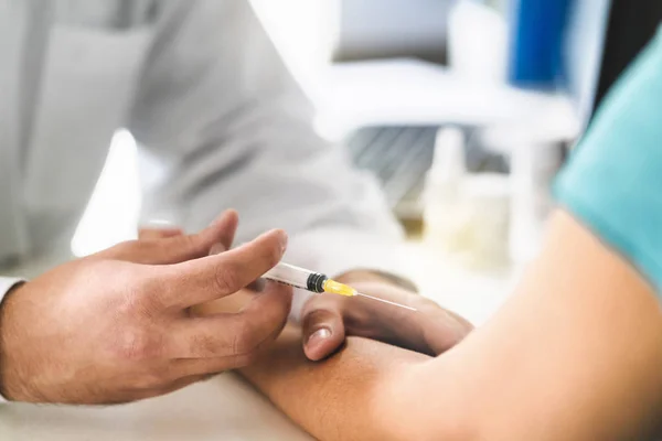 Nurse and patient taking blood test in doctor office room in hospital. Sample for studies and examination. Medical professional using needle and syringe in appointment and visit. Woman meeting medic.