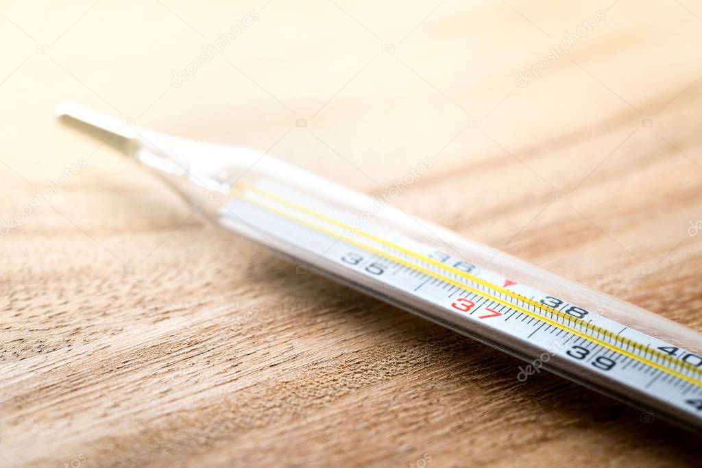 Celsius thermometer on wooden table. Having fever, flu, sickness, virus and being sick concept. Body temperature measurement in health care and medical business.