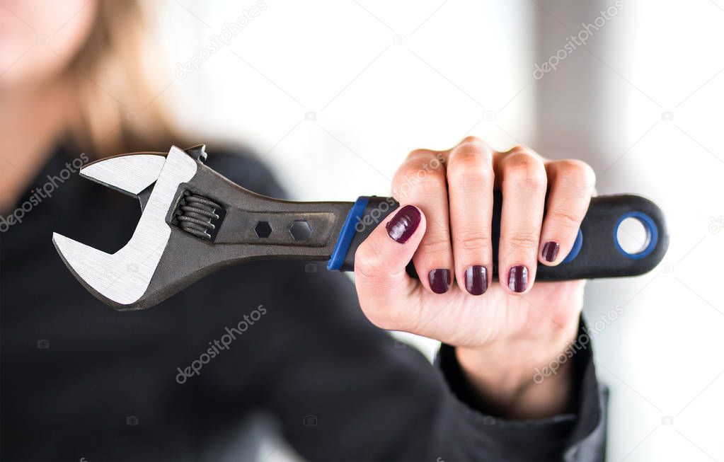 Gender roles and equality concept. Against and anti sexism, stereotypes and chauvinism. Feminism and female power. Confident and powerful woman holding tool, wrench, in hand. Female mechanic.