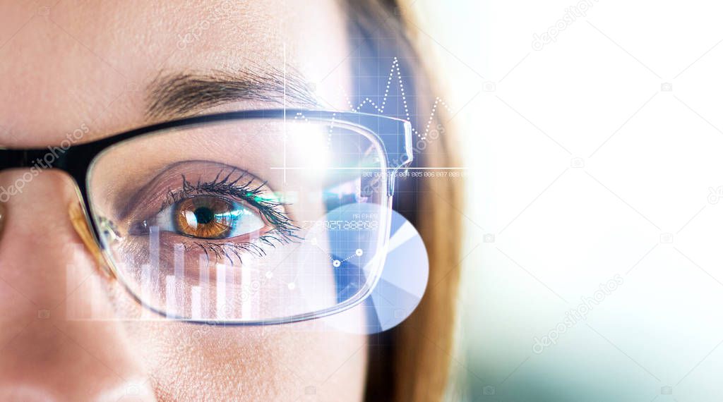 Smart glasses and augmented reality concept. Woman wearing modern spectacles with futuristic screen. Virtual technology. Close up of eye surrounded by business statistics and analytics. Future vision.