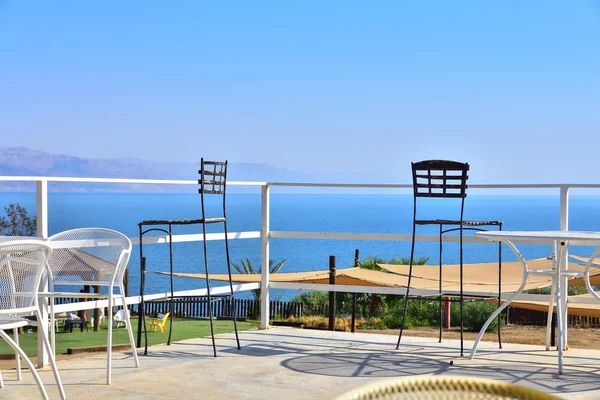 240 meters below sea level, the lowest place on the planet, view of the Dead Sea, fences, tables and chairs in the foreground, cloudless sky, coastline, Israel