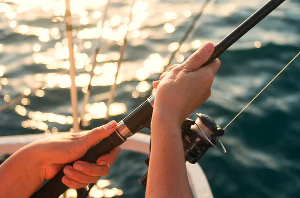 Female hand holding a fishing pole against the background of the sea. Sea fishing. The woman is fishing.