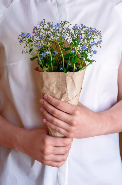 A bouquet of forget-me-nots in the hands of the girl, close-up.