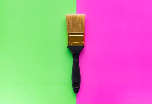 Paint brush with black pen on neon background. Pink and green neon background. The concept of minimalism.