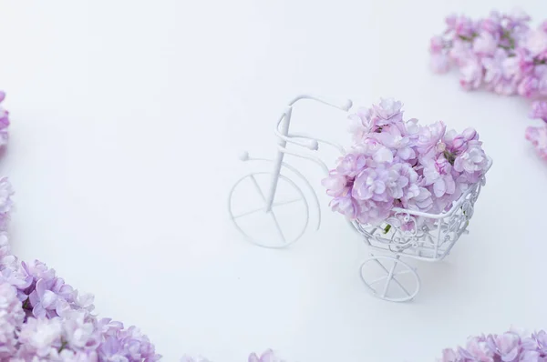 Vintage toy bike white. Bouquet of lilac, holiday decoration.