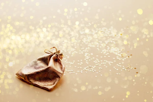 Bag of gold fabric on a background of gold stars. Festive Christmas background. Christmas gifts concept.