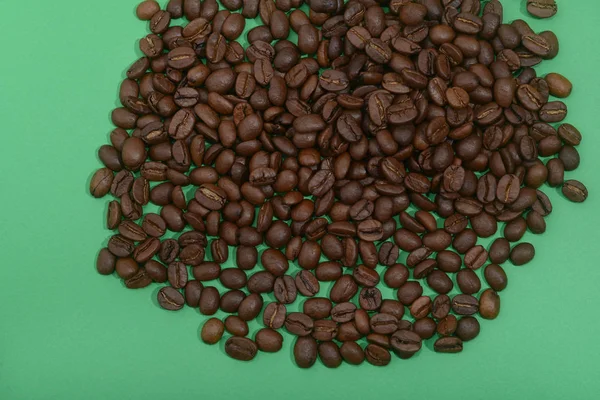 Grãos de café torrados no fundo verde — Fotografia de Stock