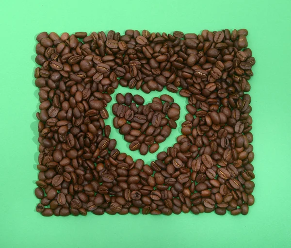 Grãos de café em forma de coração no fundo amarelo — Fotografia de Stock