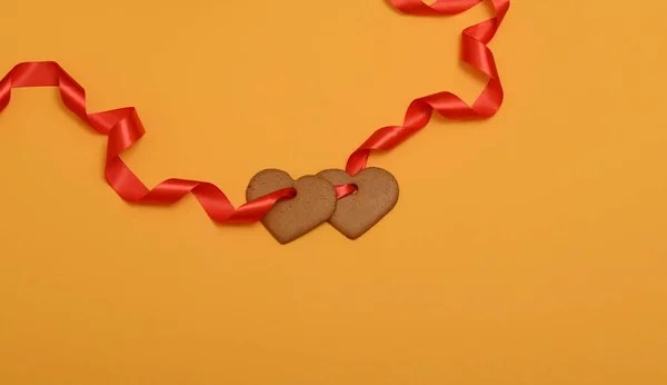 Garland of ginger cookies in shape of hearts on red ribbon — Stock Photo, Image
