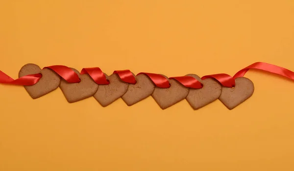 Guirnalda de galletas de jengibre en forma de corazones en cinta roja Imagen De Stock