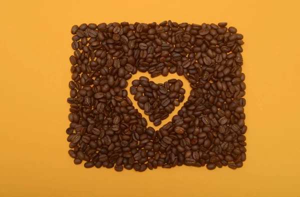 Kaffeebohnen Herzform Auf Orangenem Hintergrund Herzform Aus Kaffeebohnen lizenzfreie Stockfotos