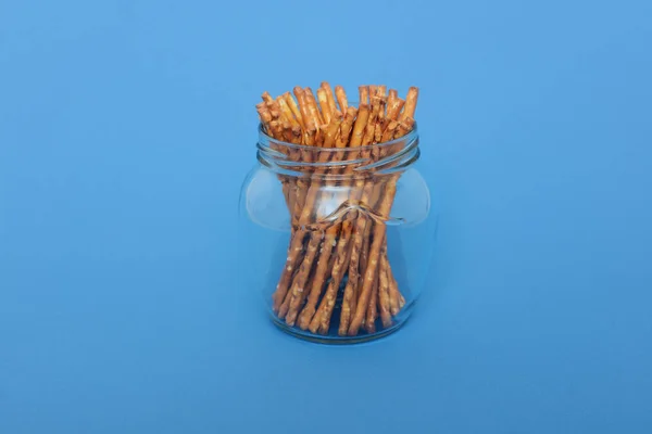 Many salted sticks in glass jar over a blue background — Stock Photo, Image