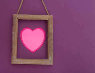 Pembe kalp mor kağıt üzerinde ahşap sınırındaki. Üstten görünüm. Sevgililer günü kartı