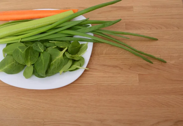 新鲜的绿色芹菜 菠菜和胡萝卜放在木制桌子上的白色盘子里 文本的空间 复制空间 素食背景 — 图库照片