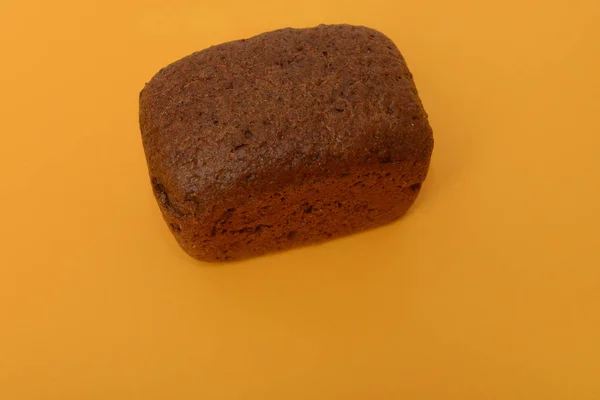 Foto de pan negro hecho a mano sobre fondo naranja Imagen de archivo
