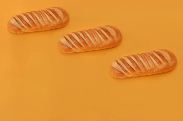 Três pães de trigo em um fundo laranja Imagem De Stock