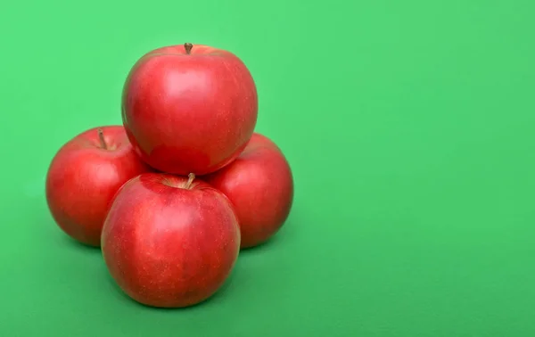Four red apples on the green background