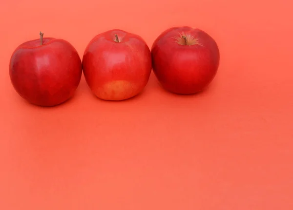 Kırmızı zemin üzerinde üç kırmızı elma — Stok fotoğraf