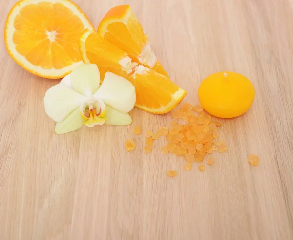 オレンジ スライスの上に蘭 木製のテーブル背景に香り塩と黄色のキャンドルの花 — ストック写真