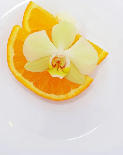 白い板の背景にオレンジのスライスの上に蘭の花 トロピカル フルーツのオレンジと分離された花の香り ストック写真