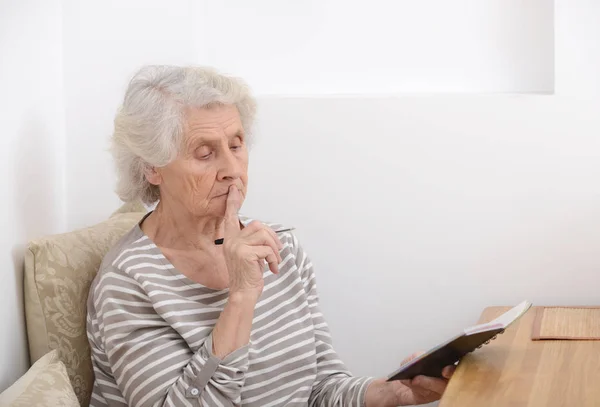 Frustrierte Seniorin sitzt mit Notizbuch am Tisch — Stockfoto