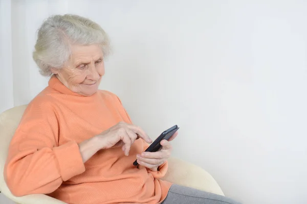 Seniorin sitzt und liest die neuesten Nachrichten auf ihrem Handy Stockfoto