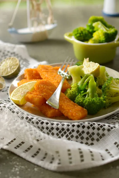 fish sticks with broccoli and lemon garnish - closeup