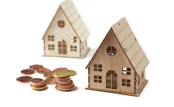 little house model on a white background with coins beside - closeup