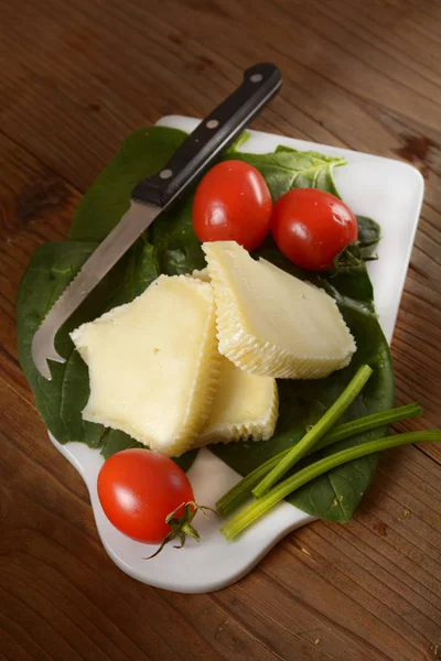 Pedaços de queijo salgado italiano com tomate cereja no corte de boa — Fotografia de Stock