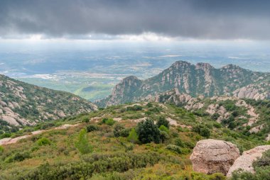 Mont yakınlarındaki yeşil ağaçlar ve bulutlu gökyüzü ile Puslu sıradışı dağlar