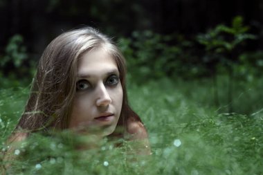 çayır çimen içinde oturan bir kız portresi