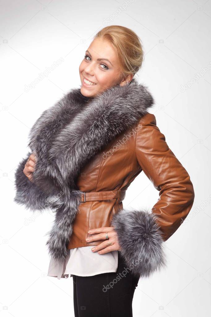 Young woman in a brown leather coat with a fur hood