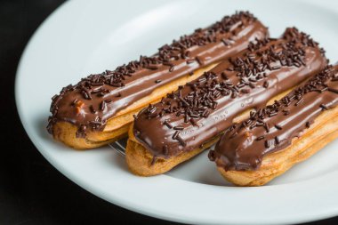 Bir tabakta çikolata krema ile Eclairs