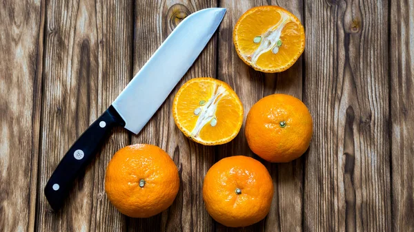 incised orange with peel and sharp knife on wooden background.