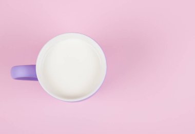 Pastel pembe arka plana karşı bir fincan süt