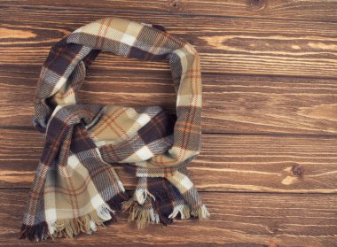 Kahverengi ahşap arka plan üzerinde rahat damalı eşarp