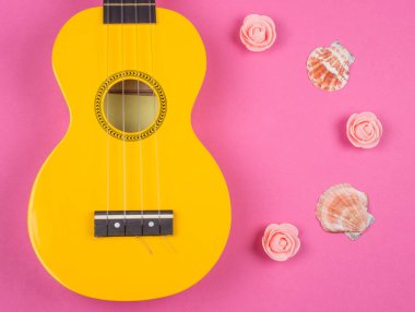 Sarı ukulele gitar, deniz kabukları ve el yapımı gül tomurcukları