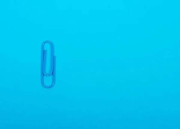 Single blue paper clip on a pastel blue background — Stock Photo, Image