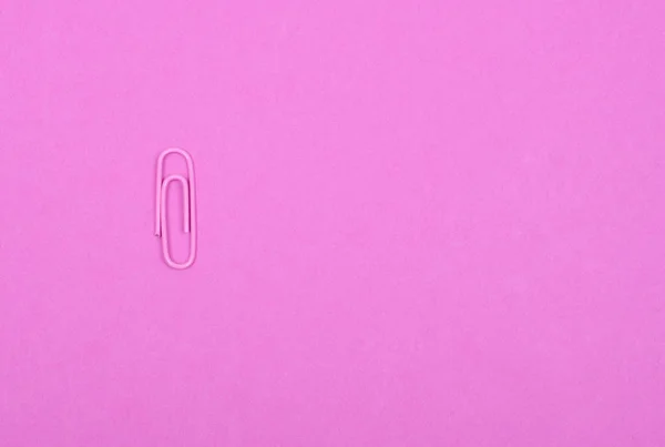 Único clipe de papel rosa em um fundo rosa pastel — Fotografia de Stock