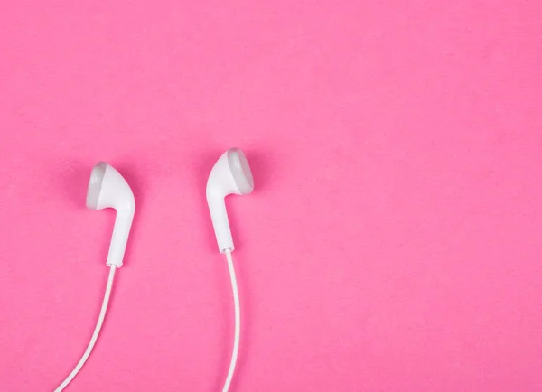 Pembe arka planda beyaz kulaklıklar