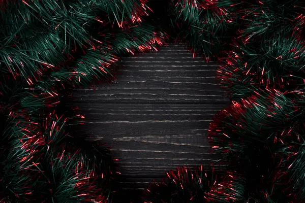 Siyah ahşap arka plan üzerinde yeşil ve kırmızı tinsel